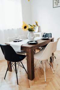 einen Esstisch mit Stühlen und eine Vase aus Blumen in der Unterkunft Apartman Noel Knin in Knin