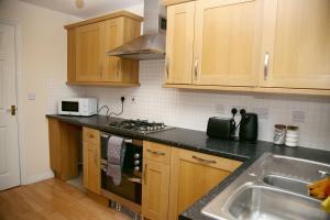 uma cozinha com armários de madeira, um fogão e um lavatório em Stylish beautiful Lodge in Norwich em Norwich