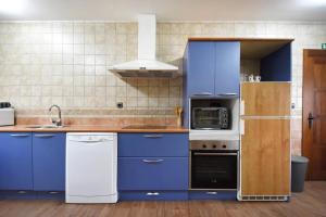 a kitchen with blue cabinets and a white refrigerator at Casa Las Torres in Navas de Oro