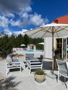 eine Terrasse mit Stühlen, einem Sonnenschirm und einem Pool in der Unterkunft Villa VitvikenB i Gotland Pool in Slite