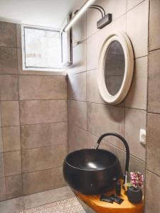 uma casa de banho com um lavatório preto e um espelho em Alegria studios em Gaios