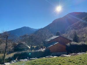 a wooden cabin on a hill with mountains in the background at CHALET DON PAPA in Saint-Martin-Vésubie