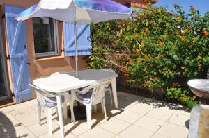 een tafel en 2 stoelen met een parasol op een patio bij Maisons du lac in Le Barcarès