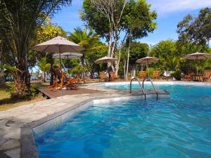 a swimming pool with chairs and umbrellas at Pousada Maliale Boipeba in Ilha de Boipeba