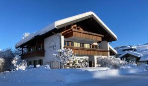 a building with snow in front of it at Goldvogel Apartments in Fischen