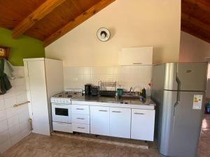 eine Küche mit einem Edelstahlkühlschrank und weißen Schränken in der Unterkunft Alta Montaña Apart in El Chalten
