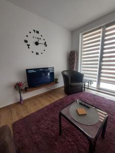 a living room with a tv and a clock on the wall at Apartman Todor in Veliko Gradište