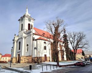 a large white church with a red roof at Apartmán na Náměstí. in Český Brod