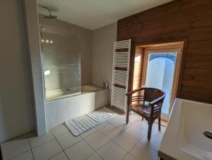ein Badezimmer mit einer Badewanne und einem Stuhl neben einem Fenster in der Unterkunft La maison de Joe in Beaumont + 5 Fotos