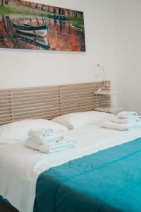 een bed met handdoeken en een schilderij aan de muur bij Dimora Mariù - Casa Vacanze in Taranto