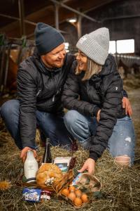 Un uomo e una donna seduti sul fieno con del cibo di Jaggling Appartements a Sankt Ulrich am Pillersee