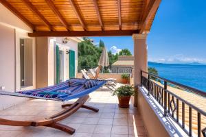 a balcony with a hammock and the ocean at Beach villa Aetos kaminaki Nissaki in Nisaki