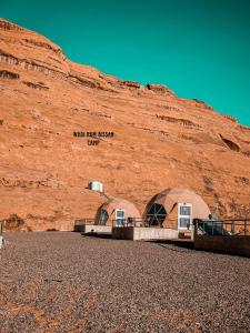 two domes sitting in front of a mountain at wadi Rum bissan camp in Disah