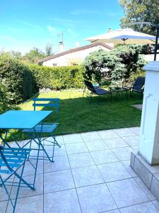 d'une terrasse avec des tables, des chaises et un parasol. dans l'établissement Studio cosy indépendant avec Jardin à Osny proche Cergy Pontoise, à Osny