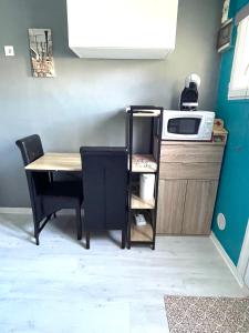 een kleine keuken met een tafel en een magnetron bij Studio cosy indépendant avec Jardin à Osny proche Cergy Pontoise in Osny