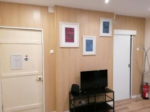 sala de estar con TV y pared con cuadros en Lisbon Heart Santa Marta Apartment en Lisboa
