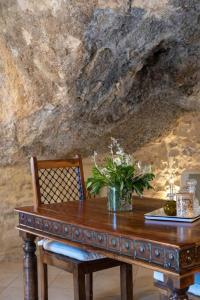 a wooden table and a chair with a plant on it at Luxurious stone cave with pool and sea view in Kissamos