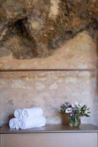 a shelf with towels and a vase of flowers at Luxurious stone cave with pool and sea view in Kissamos