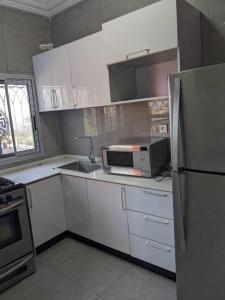 a kitchen with white cabinets and a microwave and a refrigerator at Residence Mar-Pauli in Yaoundé