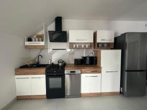 a kitchen with white cabinets and a black refrigerator at Apartament Oksford 3 in Okszów +17 photos