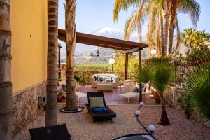 un patio con mesa, sillas y palmeras en Villa Fabiana Taormina, en Taormina