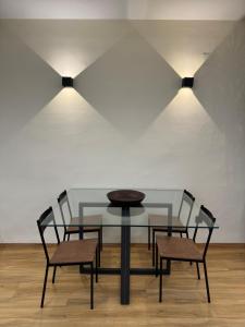 een glazen tafel met twee stoelen en twee verlichting bij SlabonHome Serrallo in Granada