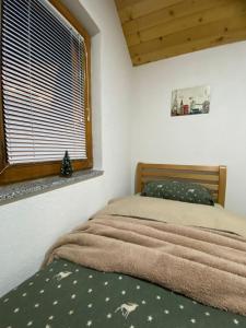 um quarto com uma cama e uma janela com um cobertor em Villa Troi Rugovë Pejë em Pec
