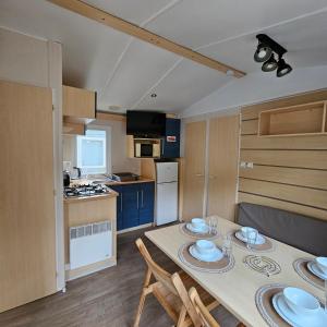 cocina y comedor con mesa y sillas en Mobil-Home – Puy du Fou (30 min), en La Boissière-de-Montaigu