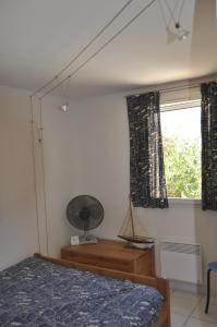 ル・バルカレスにあるMaisons du lacのベッドルーム1室(ベッド1台、ファン付きの窓付)