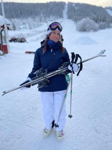 a woman standing in the snow holding skis at Åreskutans lägenhet i Huså - med laddning för bil 22 kw in Huså