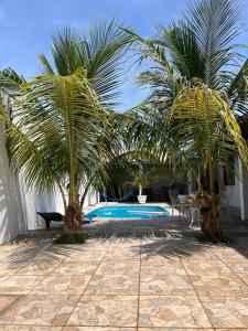 a palm tree next to a swimming pool at Morada do Zinho - Piscina, churrasqueira, lareira e 250 metros da praia in Itanhaém