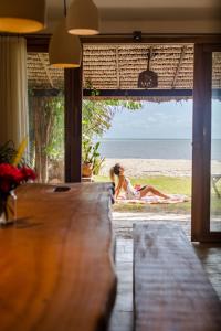 uma mulher sentada na praia a olhar para o oceano em Casa PESQUEIRA Preá - Frente Mar! em Praia do Preá