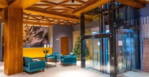 a lobby with blue chairs and a glass elevator at The Valley Bakuriani Didveli Apartment 304 in Bakuriani