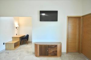 Habitación con escritorio y TV en la pared. en Hotel Plaza Rioverde, en Río Verde