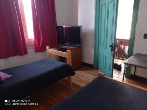 sala de estar con cama y TV en Hostal Irreal, en Santiago