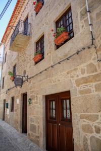 a stone building with doors and windows on a street at Casa d'Acha in São Miguel de Acha