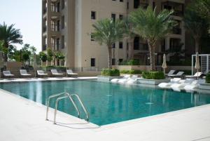 a swimming pool in a hotel with chairs and palm trees at Spectacular 2BR Apartment Full BurjAlArab View in Dubai