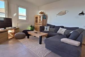 - un salon avec un canapé bleu et une table dans l'établissement Appartement Des Flamants Roses, à Palavas-les-Flots