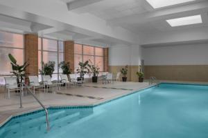 - une piscine dans une pièce avec des chaises et une table dans l'établissement Renaissance Indianapolis North Hotel, à Carmel