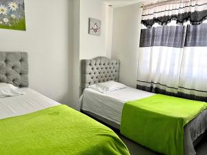 1 dormitorio con 2 camas y una ventana con sábanas verdes en Apartamento Comodo, Cerca al Rio Guatapuri en Valledupar