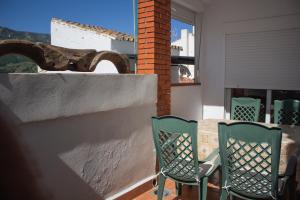 Apartamento La Luna Mora - A un paso del Caminito del Rey في Carratraca: كرسيان أخضر يجلسون على شرفة مع طاولة