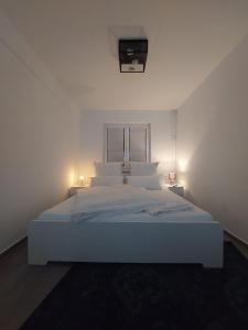 a white bed in a white room with two lights at Modern apartment cologne in Cologne