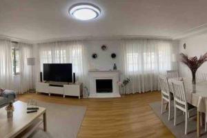 a living room with a television and a table and chairs at Casa en Playa Las Sinas in Villanueva de Arosa
