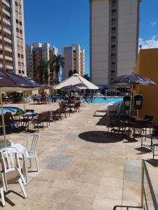 a pool with tables and chairs and umbrellas at Só alegria Eldorado Thermas in Caldas Novas