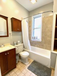 a bathroom with a toilet and a tub and a sink at Lakeview Getaway in Chicago