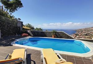 a swimming pool with two chairs and the ocean at Villa Calçada in Santa Cruz