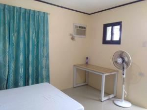 a room with a bed and a desk and a fan at Casa Esmeralda in Lupao