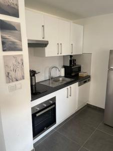 a kitchen with white cabinets and a sink and a microwave at Proche mer Appart 2 pièce Wifi&Clim in Sainte-Maxime