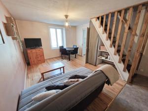 a living room with a couch and a staircase at Joli appartement rénové (Hirondelle) in Cornimont
