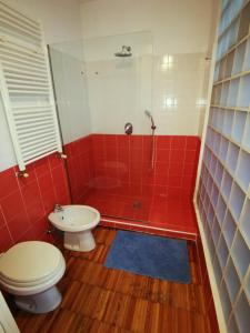 a red tiled bathroom with a toilet and a shower at In Da House in Milan